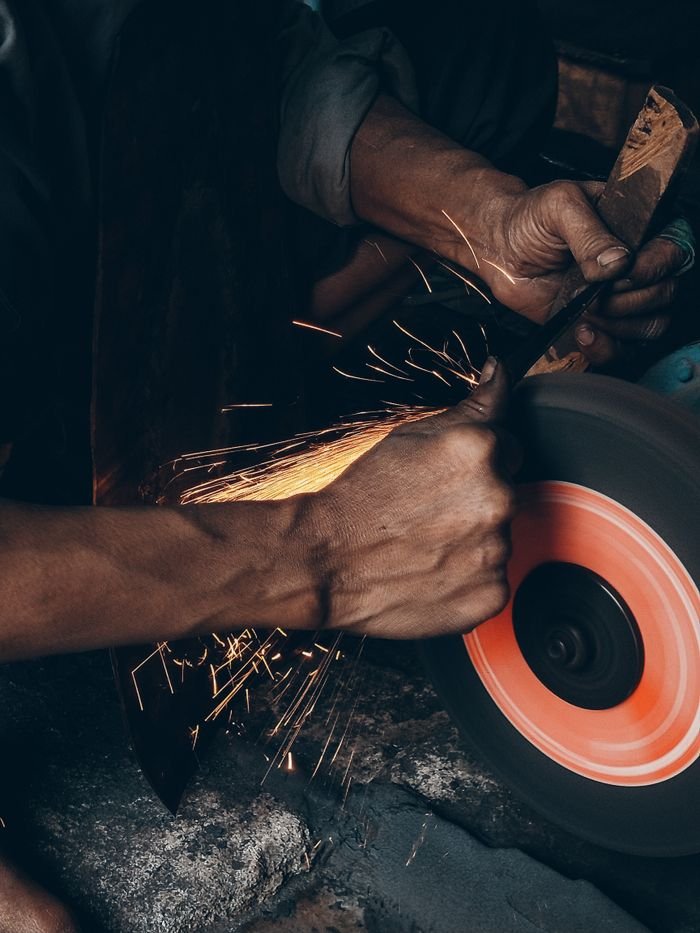Services Detailed close-up of a craftsman using a grinding wheel, creating sparks.